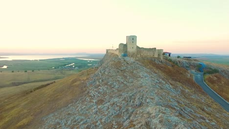 Festung-Enisala-In-Rumänien,-Drohnenschuss,-Der-Bei-Sonnenuntergang-Von-Der-Festung-Wegfliegt