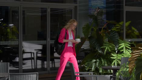 Young-stylish-woman-walks-outside-cafe-with-cup-of-coffee