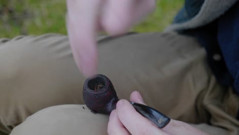 A-close-up-shot-of-a-man-packing-the-bowl-of-a-pipe-with-tobacco