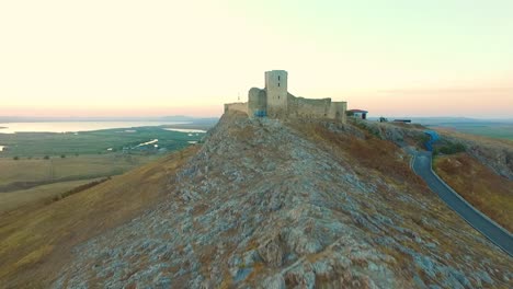 Enisala-fortress-in-Romania,-drone-shot,-flying-toward-the-fortress-at-sunset