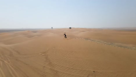 Woman-with-hula-hoop-walking-on-top-of-a-sand-dune-ridge