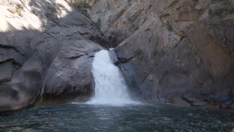 Tilting-up-shot-of-a-roaring-canyon-falls-flowing-into-a-pool-of-water