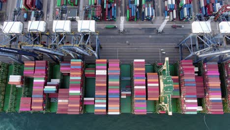 Mega-Container-Ship-docked-at-Hong-Kong-port,-during-loading-and-unloading-operation,-Aerial-view