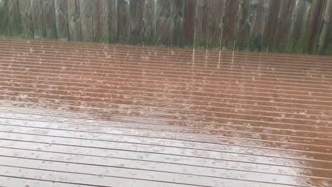 Rain-falling-on-rust-stained-deck-against-wooden-fence-during-a-winter-day-in-Auckland-New-Zealand