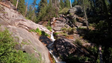 Panning-shot-following-mountain-waterfall-flowing-across-rocks