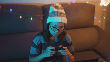 Asian-girl-wearing-glasses-gaming-at-home-with-a-wireless-controller