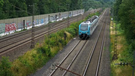 A-small-blue-commuter-train-with-only-one-car-moves-down-the-line-of-the-railroad