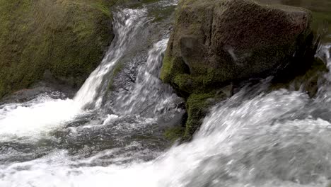 Kleiner-Wasserfall,-Der-Um-Große-Moosbedeckte-Felsen-Im-Bergbach-Fließt