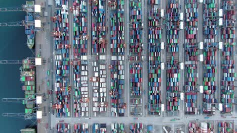 Mega-Container-Ship-docked-at-Hong-Kong-port,-during-loading-and-unloading-operation,-Aerial-view