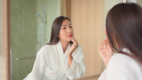 Schöne-Asiatische-Frau,-Die-Sich-Im-Spiegel-Betrachtet-Und-Ihre-Gesichtshaut-Nach-Kosmetik-Und-Spa-behandlung-überprüft