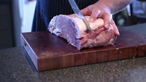 A-Man-Cutting-A-Fresh-Meat-On-The-Wooden-Board-Using-A-Knife---Close-Up-Shot