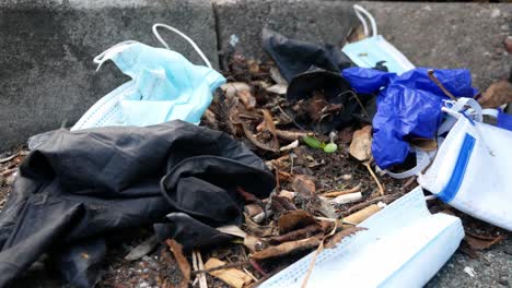 Dirty-disposable-corona-virus-face-masks-and-latex-gloves-among-cigarette-filthy-rubbish-on-street-curb-push-in-forwards