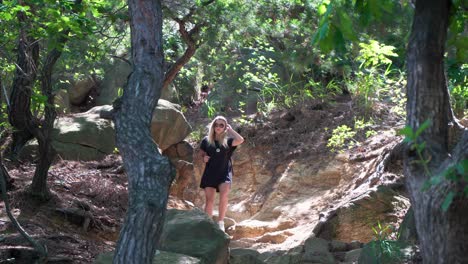 Active-girl-hiking-down-rocky-path-in-shade-of-trees-that-block-sunlight,-static