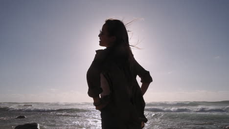 Zeitlupenaufnahme-Einer-Lächelnden-Frauensilhouette,-Die-Bei-Sonnenschein-Am-Strand-Posiert