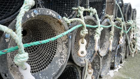 Fishing-harbour-group-of-stacked-lobster-pots-on-coastal-marine-waterfront-close-up-dolly-right