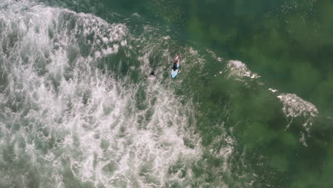 Surfer-paddles-out-with-instructor-into-breaking-waves