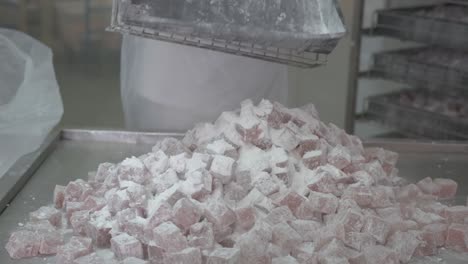 A-factory-worker-dumps-a-large-tray-of-finished-Turkish-Delight-squares-onto-a-table-for-packaging