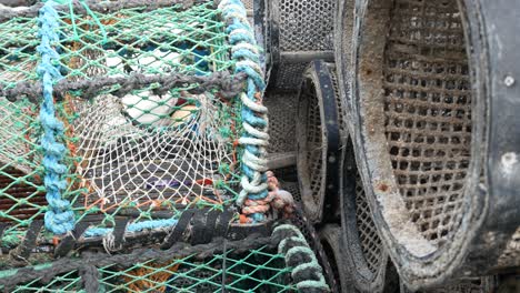 Close-up-Fishing-harbour-group-of-stacked-lobster-pots-on-coastal-marine-waterfront-dolly-right