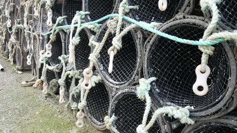 Close-up-Fishing-harbour-group-of-stacked-lobster-pots-on-coastal-marine-waterfront-pull-back