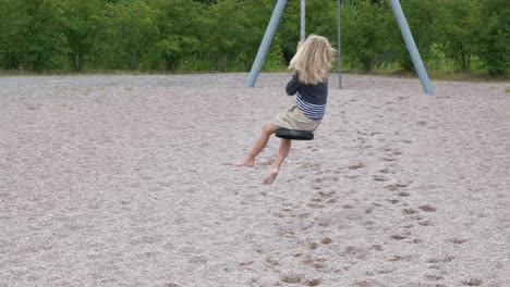 Young-blond-girl-plays-with-zip-line-at-playground,-slow-motion-shot