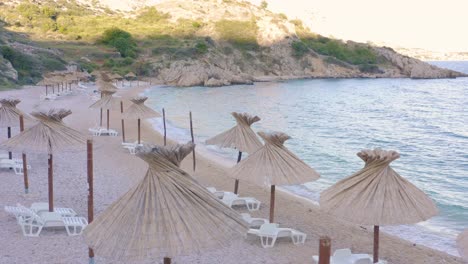 Parasols-And-White-Sun-Loungers-In-A-Lovely-Beach-In-Krk-Island,-Croatia---Perfect-Summer-Destination---drone-shot