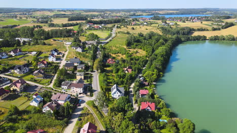 Aerial-view-of-luxury-rural-housing-area-beside-beautiful-lake-in-countryside-during-sunrays