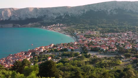 The-Lush-Green-Trees-By-The-Mountains-Overlooking-The-Scenic-Town-of-Baska-And-The-Calm-Bue-Sea-In-Krk,-Island,-Croatia