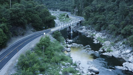 Bridge-spans-over-calm-stream-in-remote-backwoods-of-America,-aerial-sideways