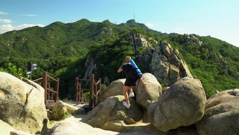 Girl-Walking-Towards-The-Boulders-And-Almost-Slipped-When-Climbing---Girl-Standing-On-The-Rocks-And-Enjoying-The-natural-View-From-Gwanaksan-Mountain-With-Open-Arms-Overhead