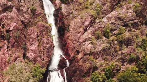 Flying-over-flowing-waterfall-along-cliff-face