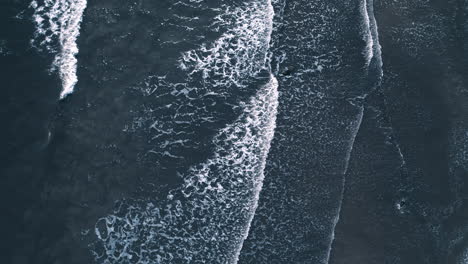 Aerial-view-from-above-of-water-from-sky-foamy-waves-at-wave-beach-hitting-shore-slowly-calm-meditation-yoga-footage-of-ocean-sea-water-on-island-heli-aerial-coastal-line-with-no-people-at-pier-harbor