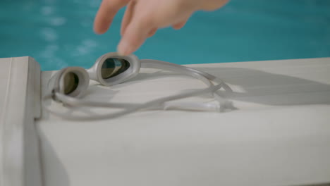 Hand-picks-up-poolside-goggles
