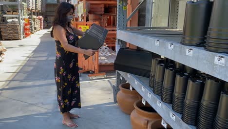 Female-wearing-protective-corona-virus-mask-checking-planters-in-home-depot-garden-centre