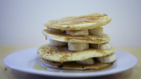 Leckeres-Frühstück-Mit-Gestapelten-Bananenpfannkuchen-Mit-Sirup,-Der-Die-Schichten-Heruntertropft,-Nahaufnahme