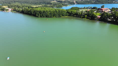 Panning-drone-shot-of-inhabited-island-beside-epic-nature-lake-during-summer-and-blue-sky
