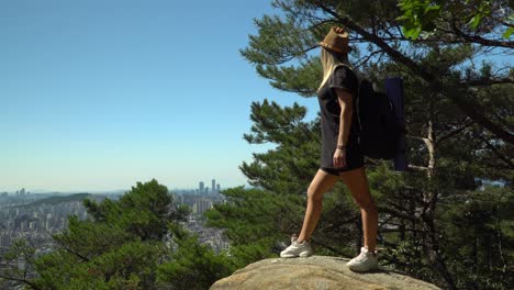 Girl-Standing-On-The-Boulders-And-Looking-At-The-Scenic-Downtown-Skyline-In-Seocho-gu-District-From-Gwanaksan-Mountain-In-Seoul,-South-Korea