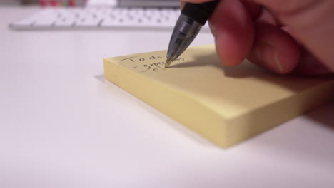 Man-writing-to-do-list-on-yellow-notepad