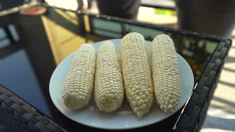 Placing-freshly-husked-sweet-corn-on-a-glass-plate