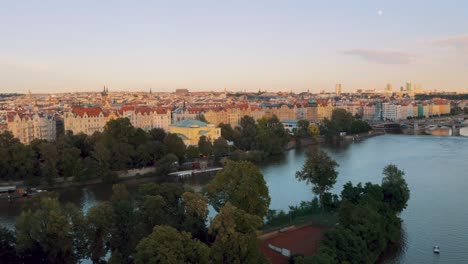 Golden-hour-aerial-drone-shot-over-Vltava-Prague-river,-cityscape-Czech-Republic
