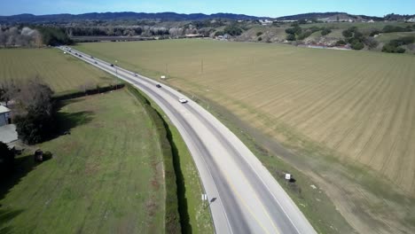 Aerial-view-following-Santa-Barbara-traffic-vehicles-driving-along-countryside-freeway