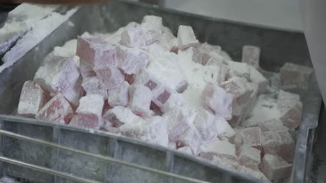 A-factory-worker-removes-the-finished-squares-of-Turkish-delight-from-a-conveyor-belt-and-places-them-on-a-tray