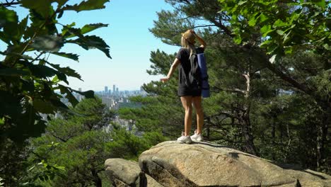 Hiking-girl-spreads-arms-out-of-joy,-feeling-happy-being-outdoor-in-fresh-air,-Seoul-in-distance