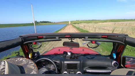 POV-Driving-on-a-flooded-graveled-road-in-rural-South-Dakota-between-a-flooded-pond-and-Marsh-area