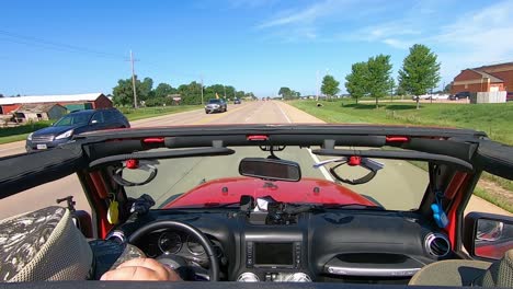 POV-Driving-on-a-paved-road-in-rural-South-Dakota,-wind-catching-drivers-hat
