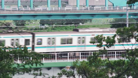 Two-JR-Trains-Passing-By-On-The-Bridge-in-Tamagawa-At-Daytime-In-Tokyo,-Japan
