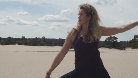 Beautiful-woman-doing-warrior-pose-in-sand-dunes