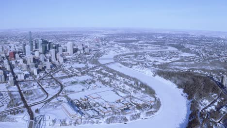 HIgh-above-aerial-over-winter-downtown-city-panout-of-Edmonton-Alberta-Canada-with-snow-covered-North-Saskatchewan-River-with-highways,-bridges,-forest-park-stunning-clear-skys