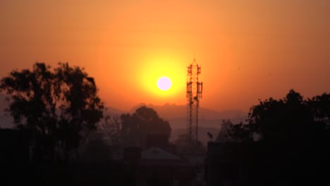 Reveal-shot-of-beautiful-golden-sunrise-in-slowmotion,-silhouette-of-a-bird-fly-by,-Mumbai,-India
