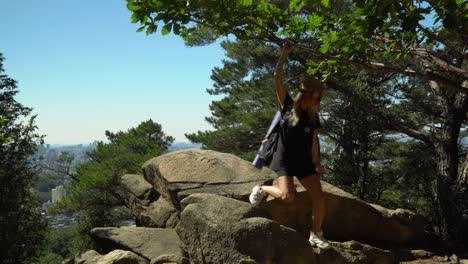 Caucasian-Girl-Going-Down-On-The-Boulders-After-Looking-At-The-Scenic-Landscape-From-Gwanaksan-Mountain-Under-The-Bright-Blue-Sky-In-Seoul,-South-Korea