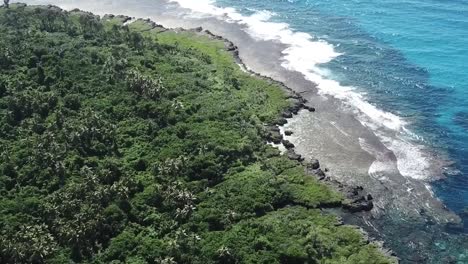 Stunning-blue-beach-water-with-rocky-shoreline-and-black-sand-blue-lagoon-vanuatu